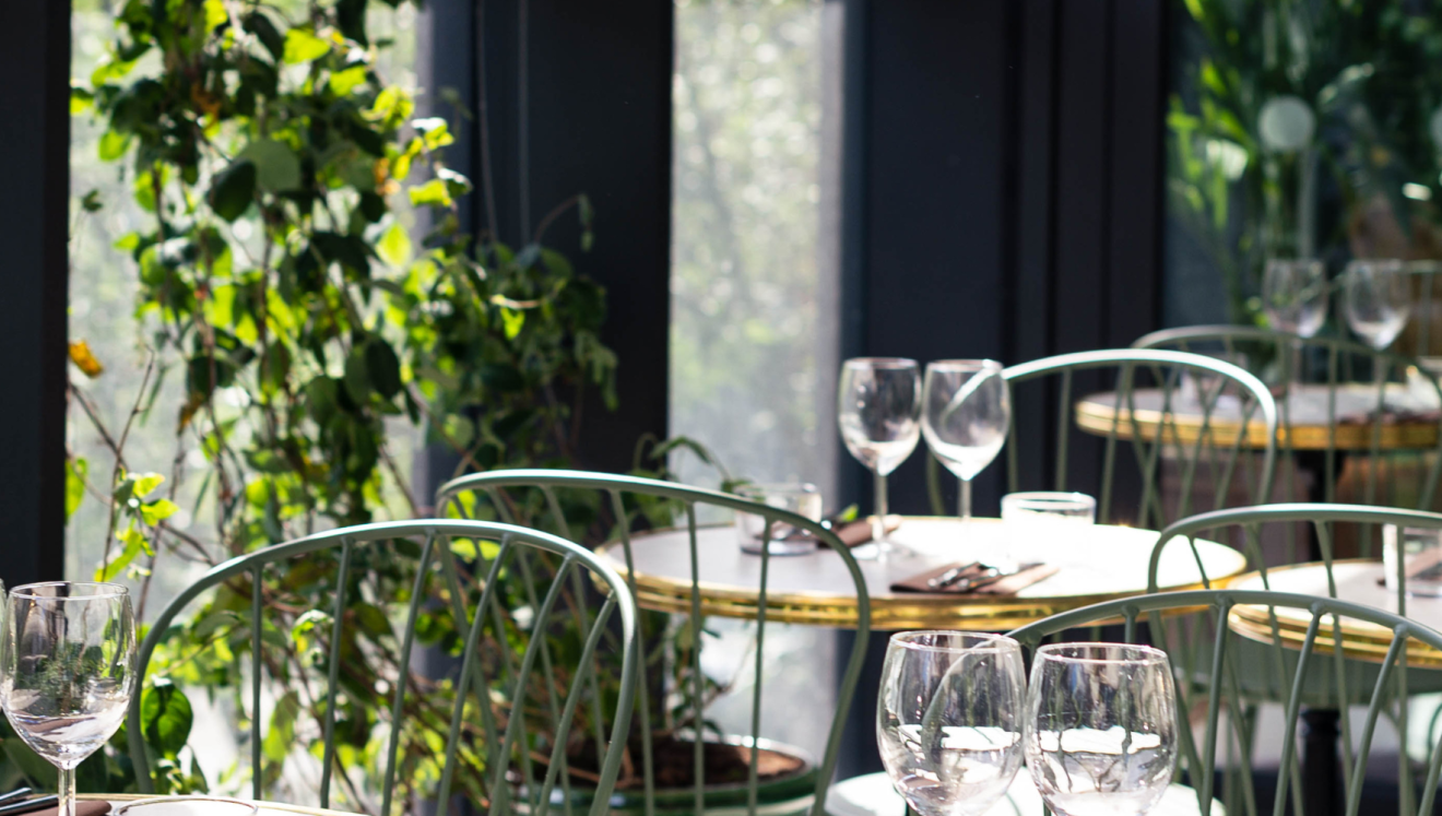 Tables de restaurant contre une fenêtre avec des plantes