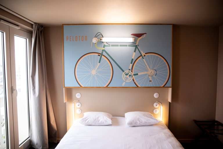 Twin bed in private room with painting of bicycle on the wall