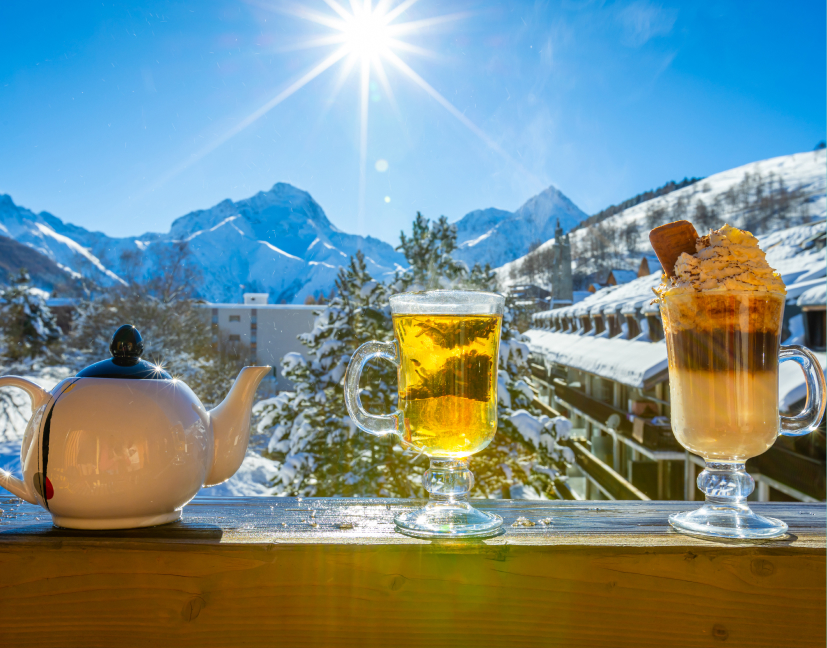 Théière et boissons sur une rambarde devant un paysage de montagnes enneigées